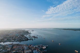 Vista aérea do porto de Manaus, com embarcações no Rio Negro e a paisagem urbana ao fundo