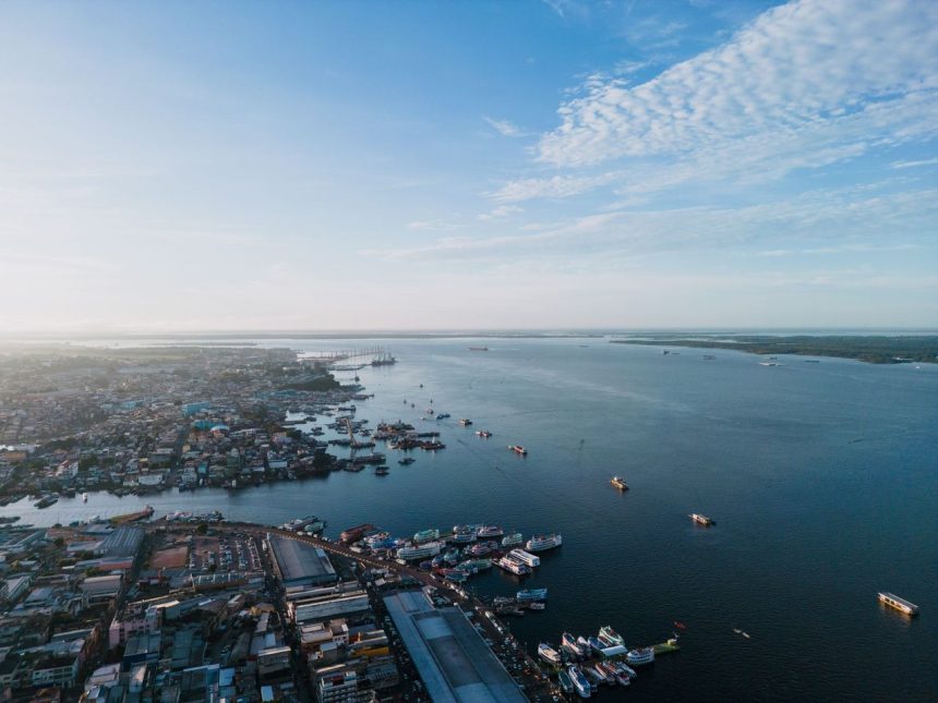 Vista aérea do porto de Manaus, com embarcações no Rio Negro e a paisagem urbana ao fundo
