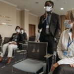 Profissionais de saúde usando máscaras participam de uma reunião em ambiente interno.